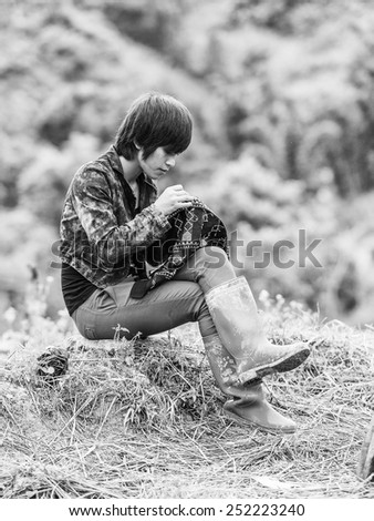 TA PHIN, LAO CAI, VIETNAM - SEP 21, 2014:  Unidentified Red Dao boy sews on the stone. Red Dao is one of the minority ethnic groups in Vietnam