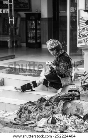 SAPA, VIETNAM - SEP 20, 2014: Unidentified Hmong woman in a traditional dress sews in the street. Hmong people is a minority ethnic group living in Sapa