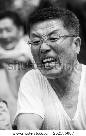 NORTH KOREA - MAY 1, 2012: Korean woman emotionally participates in the tug of war game during the celebration of the Worker\'s Day in N.Korea, May 1, 2012. May 1 is a national holiday in 80 countries