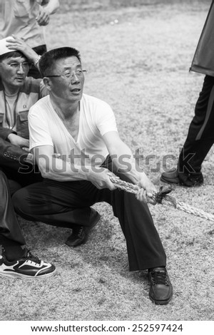 NORTH KOREA - MAY 1, 2012: Korean man emotionally participates in the tug of war game during the celebration of the Worker\'s Day in N.Korea, May 1, 2012. May 1 is a national holiday in 80 countries