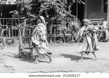 OMO, ETHIOPIA - SEPTEMBER 19, 2011: Unidentified Ethiopian women in old clothes run  in the street. People in Ethiopia suffer of poverty due to the unstable situation