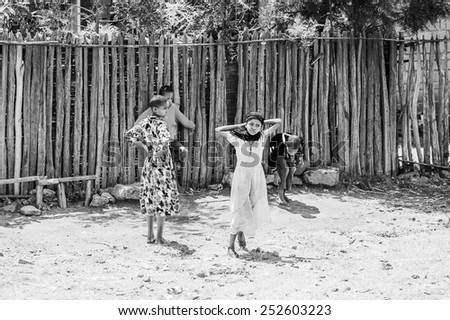 OMO, ETHIOPIA - SEPTEMBER 19, 2011: Unidentified Ethiopian girls run near the wooden fence.  People in Ethiopia suffer of poverty due to the unstable situation