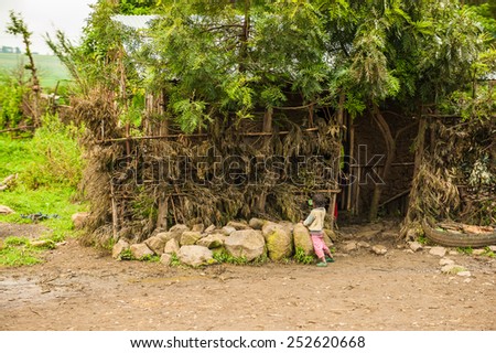 OMO, ETHIOPIA - SEPTEMBER 19, 2011: Unidentified Ethiopian little girl neat a wooden house. People in Ethiopia suffer of poverty due to the unstable situation