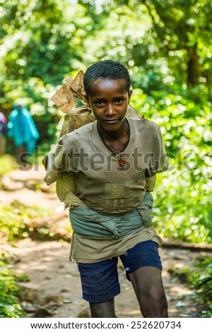 OMO, ETHIOPIA - SEPTEMBER 20, 2011: Unidentified Ethiopian boy carries a bag on his back. People in Ethiopia suffer of poverty due to the unstable situation