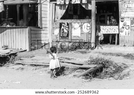 ANTANANARIVO, MADAGASCAR - JUNE 29, 2011: Unidentified Madagascarlittle girl runs near a shop. People in Madagascar suffer of poverty due to the slow development of the country