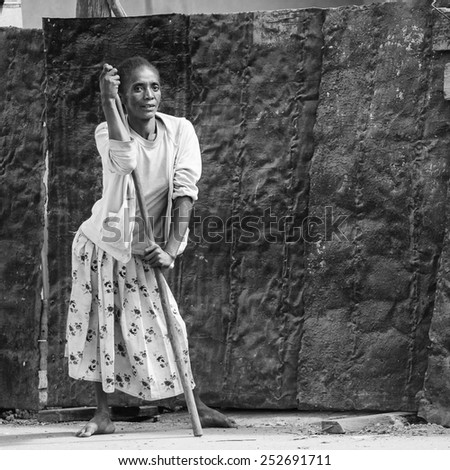 ANTANANARIVO, MADAGASCAR - JUNE 30, 2011: Unidentified Madagascar woman stays with a stick and stays in the street. People in Madagascar suffer of poverty due to slow development of the country