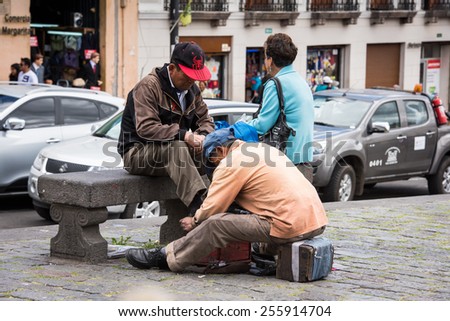 QUITO, ECUADOR - JAN 2, 2015: Unidentified Ecuadorian man cleans shoes. 71,9% of Ecuadorian people belong to the Mestizo ethnic group