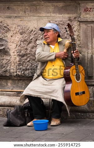 QUITO, ECUADOR - JAN 2, 2015: Unidentified Ecuadorian man plays guitar and gains money in the street. 71,9% of Ecuadorian people belong to the Mestizo ethnic group