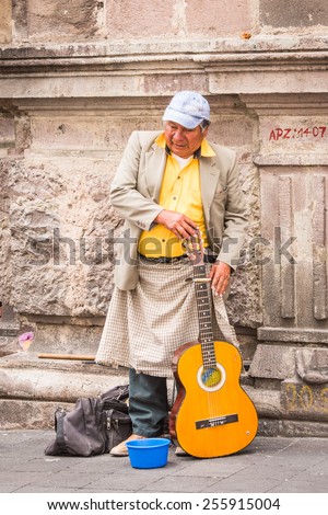 QUITO, ECUADOR - JAN 2, 2015: Unidentified Ecuadorian man plays guitar and gains money in the street. 71,9% of Ecuadorian people belong to the Mestizo ethnic group