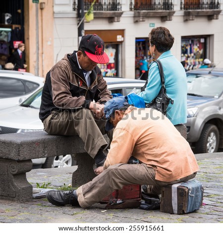 QUITO, ECUADOR - JAN 2, 2015: Unidentified Ecuadorian man cleans shoes. 71,9% of Ecuadorian people belong to the Mestizo ethnic group