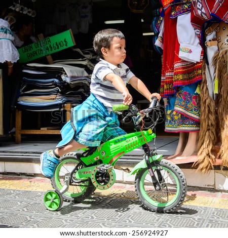 OTAVALO, ECUADOR - JAN 3, 2015: Unidentified Ecuadorian little boy on bike at the Otavalo Market. 71,9% of Ecuadorian people belong to the Mestizo ethnic group