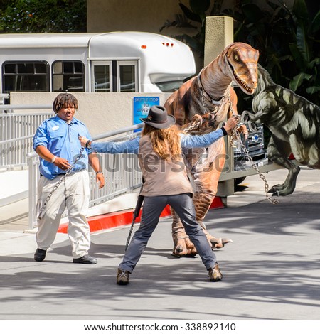 LOS ANGELES, USA - SEP 27, 2015: Velociraptor escorted by unidentified people in Jurassic Park area in the Universal Studios Hollywood Park. Jurassic Park is a 1993 adventure film