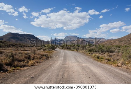 A dirt track leads invitingly into the mountains on a sunny summer\'s day in the Karoo, South Africa