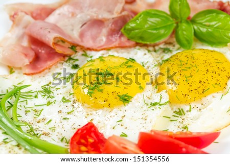 Fried eggs with bacon, basil and tomatoes