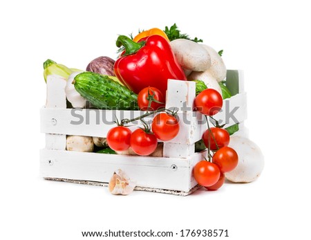 Fresh vegetables in a painted wooden box isolated on white background