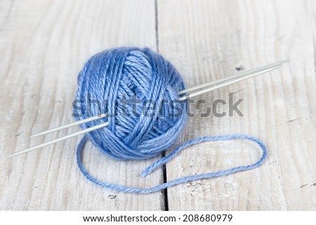 Clew of wool yarn with needles on wooden background