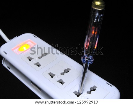 Screwdriver with electrical tester working on electrical outlet.