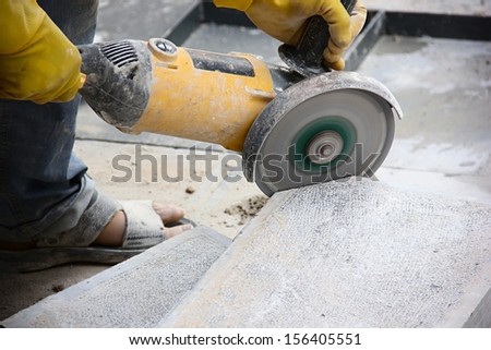 Worker cutting stone block by cutter machine.