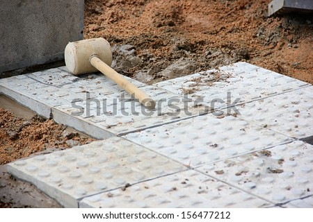 Hammer on tiles. Paving tiles on street.