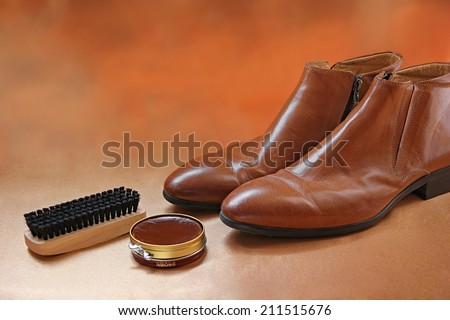 Brown boots with shoe polish and brush shoe care background.