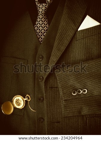 Men's black suit with golden pocket watch. Sepia image.