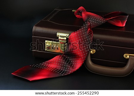 Leather suitcase with red silk tie.