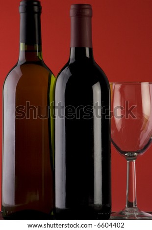 Two Bottles of red wine with a wine glass on a plain background