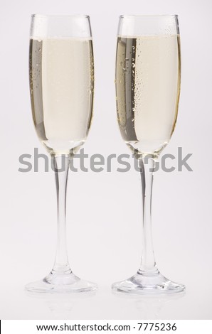 Two glass champagne flutes against a plain background.
