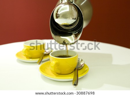 A coffee pot with yellow coffee cups.