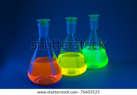Chemical flasks with the liquids, shone different colors on a dark blue background. Shallow depth of field.