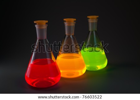 Chemical flasks with the liquids, shone different colors on a dark grey background.