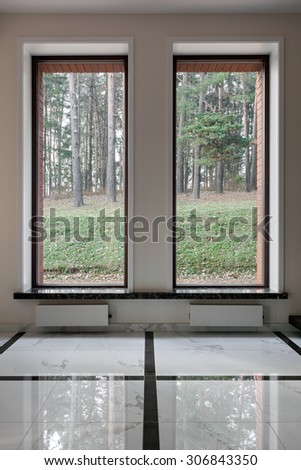 Interior of modern empty space with big windows and forest on the background