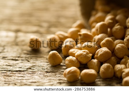 scattered chickpeas from a jute bag on old wooden background