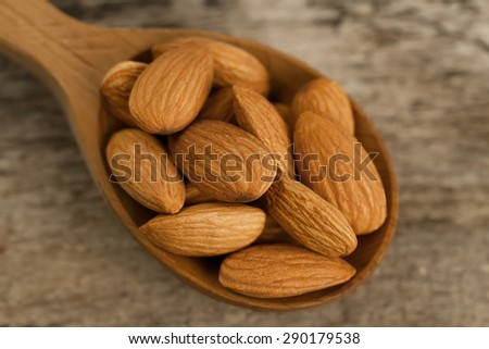 peeled almonds in spoon on wooden background. For vegetarians