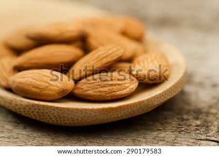 peeled almonds in spoon on wooden background. For vegetarians
