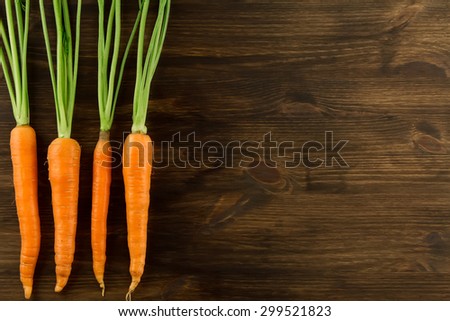 Bunch of fresh carrots with green leaves on wooden background. Healthy vegetarian food