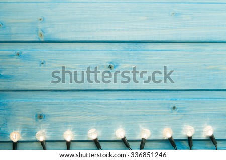 yellow Christmas lights on a blue wooden background.