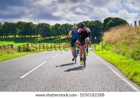 Two cyclists on a cycling tour on country roadson a sunny day in the UK.
