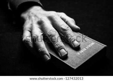 A mans hand holding the Holy Bible.