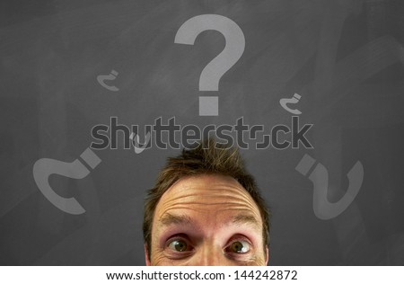 Mans head with chalk question marks on a blackboard.
