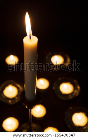 Lit candles and tealights on a dark background.