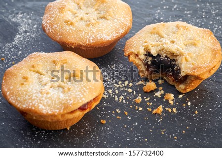 Sweet Christmas mince pies on a Slate cooling board with a bite missing from one.
