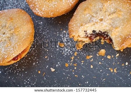 Sweet Christmas mince pies on a Slate cooling board with a bite missing from one.
