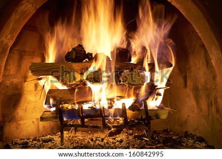 A log fire burning furiously in a stone fire place.