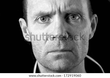 A close up of a mans face in black and white with an intense stare.