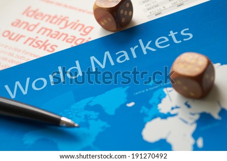 World markets documents with dice and pen.