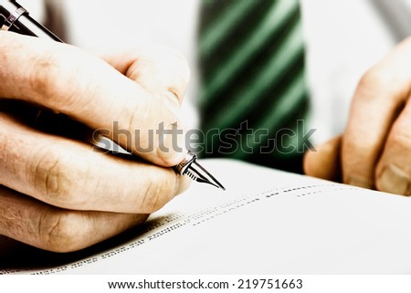 A hand holding a fountain pen and about to writer a note or highlight some text for correction. Styling and small amount of grain applied.