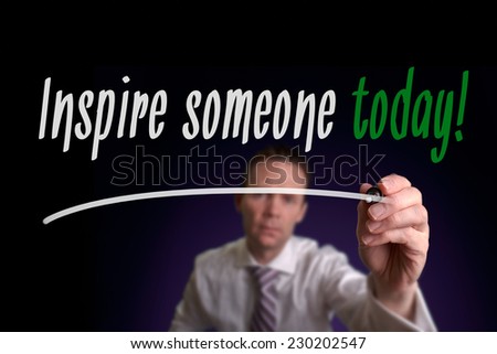A businessman writing Inspire Someone Today on a screen. Business Concept.
