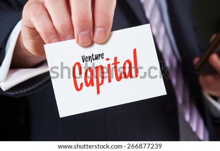 A businessman holding a business card with the words, Venture Capital, written on it.