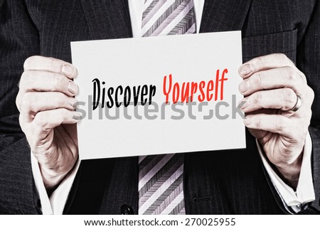 A businessman holding a card with the words, Discover Yourself.